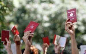 Myanmar nationals hold up their passports outside the embassy of Myanmar in Singapore